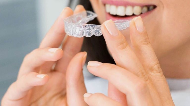 a lady is putting clear aligners